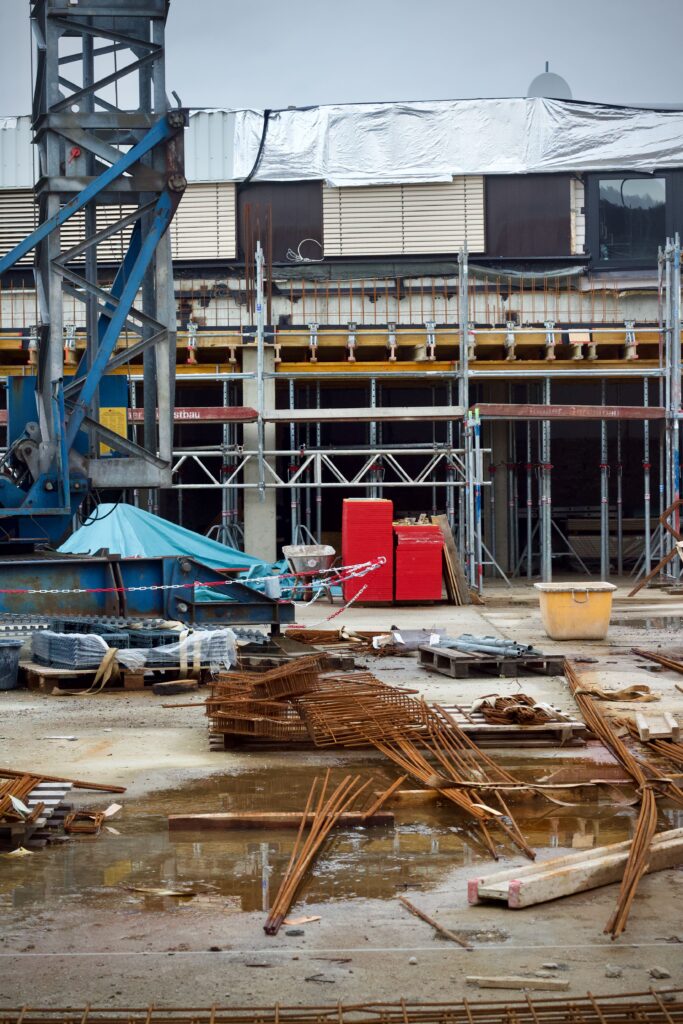 Industrial construction site with scattered materials and equipment on a rainy day.